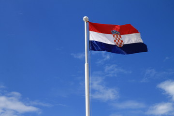 Flag of Croatia with flag pole waving in the wind with blue sky in background