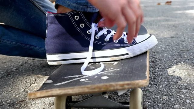 Close up detail view of a skater tying his shoes and riding skate board, sport and recreation lifestyle