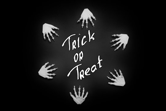 Black Halloween background with White skeleton hands, trick or treat
