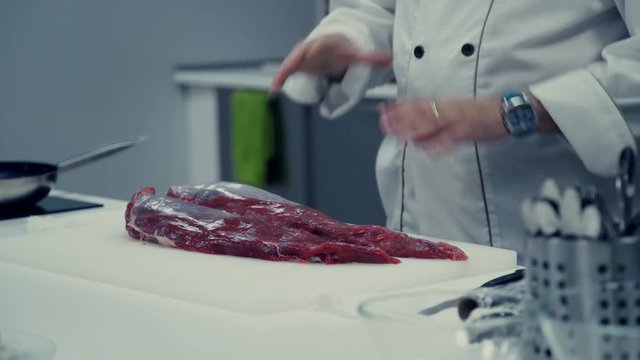 A piece of juicy beef tenderloin on a cutting board. Juicy beef. The hands of the chef. The chef prepares succulent and fragrant roast. for roast meat. Culinary master class. cuisine