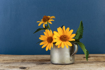 Wild flowers in an aluminum mug on a wooden table