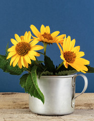 Wild flowers in an aluminum mug on a wooden table