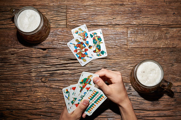 Hände beim Kartenspiel mit Bier