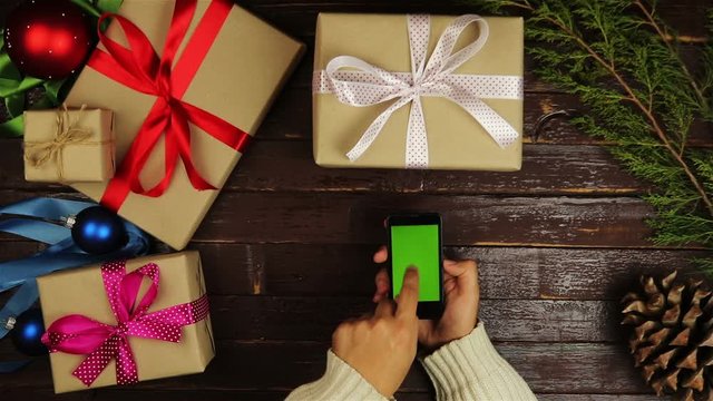 Top view hands using mobile phone touchscreen multi touch gestures green screen on christmas wooden table