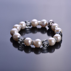 Pearl bracelet with crystals on a dark background. Beadwork.