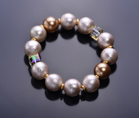 Pearl bracelet with crystals on a dark background. Beadwork. Top view.