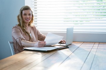 Woman looking at bill while using laptop