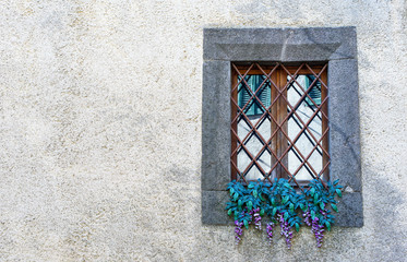 window with iron grating and artificial flowers - 124907174