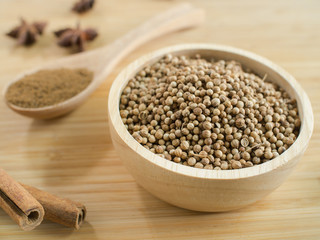 Coriander seeds in wooden bowl  and on wooden board.