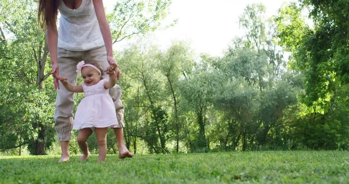 On a sunny day a baby takes its first steps on its own and in the hands of the newborn is a pinwheel, smiling and happy baby falls but rises again.