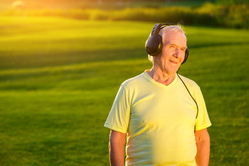 Older man with headphones. Person on green meadow background. My favorite radio station. Re-listen...