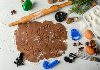 Fototapeta na wymiar Making traditional christmas gingerbread cookies. Christmas-tree branches, a rolling pin, whisk for whipping eggs, nuts and cones they lie on a table nearby