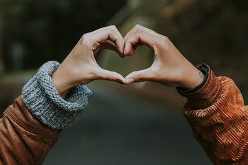 hands linked with heart sign outdoors