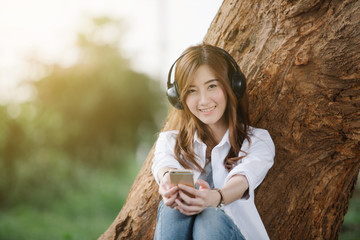 Young Asia woman listening to music in city park