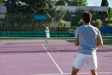 Professional tennis player playing the game on the tennis court. He has his back to the camera and have the racket in his right hand. 