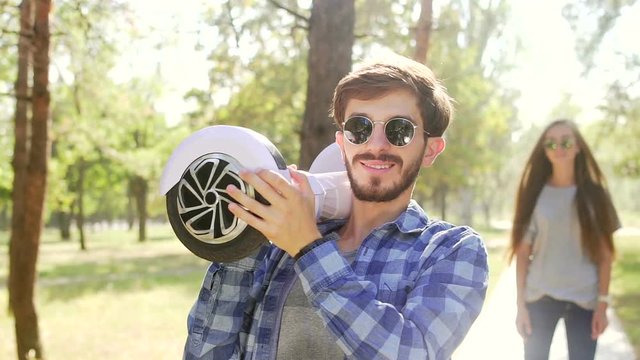 Handsome man standing with gyroscooter and girl come over, kiss and thumbs up