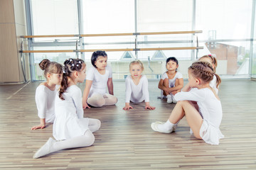 Fototapeta premium group of seven little ballerinas sitting on the floor. They are 