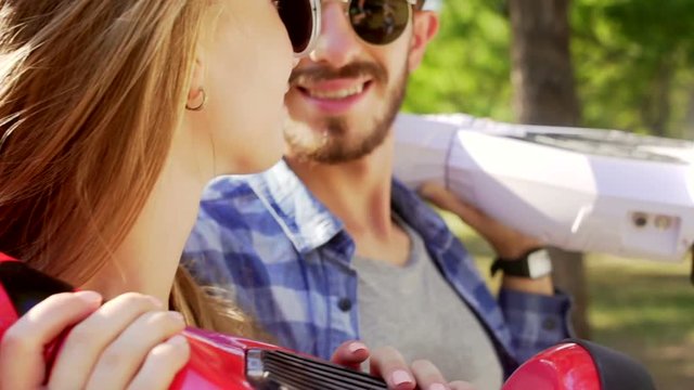 Modern couple kissing and laughing while holding hoverboards