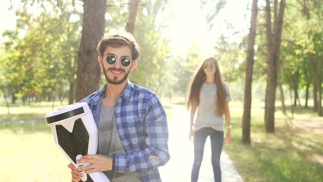Handsome man standing with gyroscooter and girl come over and kiss