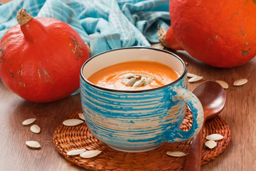 Pumpkin soup with seeds / Pumpkin soup with seeds in blue cup on rustic wooden background