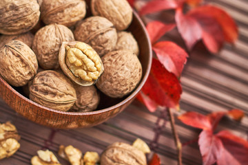 Walnuts in wooden bowl on wooden background