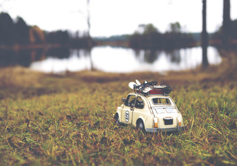 Miniature car is traveling around the world. Caricature car is wondering on the shore. Image has a vintage effect applied.
