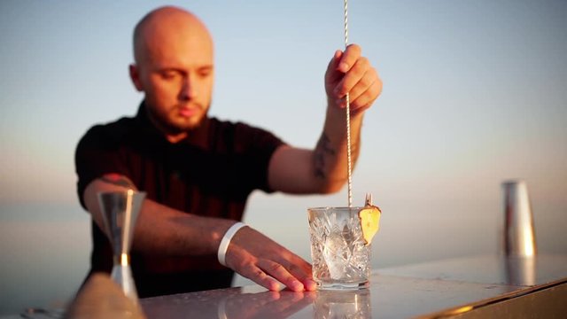 Young handsome bartender preparing cocktail at seashore Slow motion