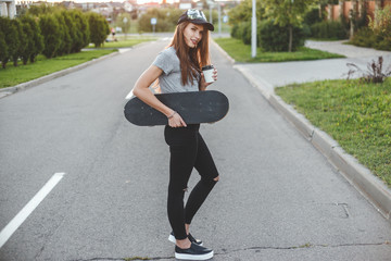 skater girl with coffee cup in front of the sun starts her day. © vladdeep