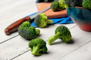 Broccoli scattered on white wooden table.selective focus.knife on the second paln defocused