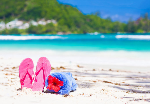 pink flip flops and blue towel on a tropical Seychelles beach. Mahe island