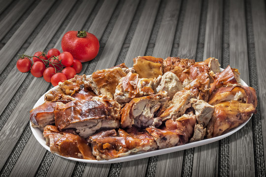 Plateful of Spit Roasted Pork Slices With Bunch Of Fresh Ripe Juicy Tomatoes Set On Rustic Wooden Background
