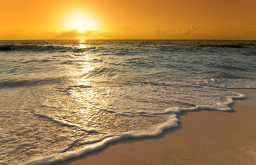 golden sunrise with wave over caribbean beach