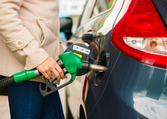 Woman fills petrol into her car at a gas station