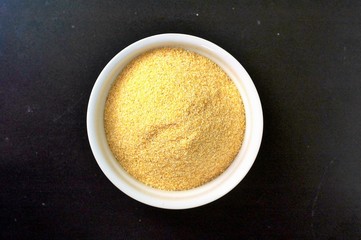 Corn flour polenta in white bowl on black background