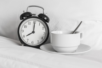 Fototapeta na wymiar Still life with vintage alarm clock and coffee cup on bed ( alar