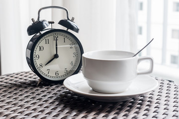 Fototapeta na wymiar Still life with vintage alarm clock and coffee cup on weave tabl