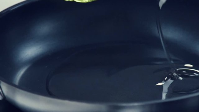 Oil on red-hot frying pan. Sunflower oil. Vegetable oil. Olive oil. The oil poured on a pan. Oil for frying. Cooking. Dinner. Pouring mustard oil onto frying pan. Bottle with pouring oil
