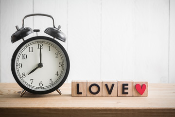 Vintage alarm clock with "love" in cube on wood table