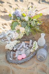 Obraz na płótnie Canvas Beautiful stylish decoration with a bouquet and macaroons near the stone on the beach of a sea. Wedding design