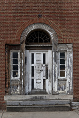 Fototapeta na wymiar Elegant, weathered white door with aging, ornate details on vintage brick wall