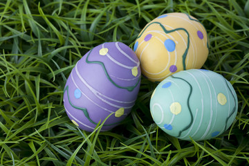 Three colorful Easter eggs hiding in bright green grass.