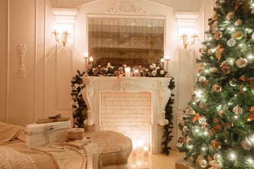 Christmas evening by candlelight. classic apartments with a white fireplace, decorated tree, bright sofa, large windows