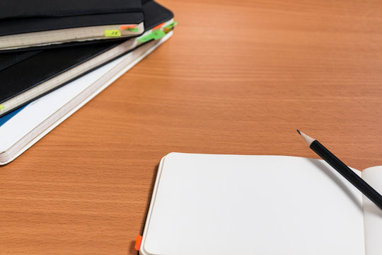 Working space with closed old notebooks with colored bookmarks and one open notebook with pencil. Old style work concept. Business without gadgets concept.