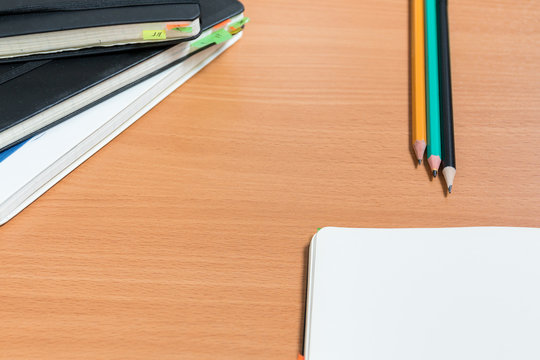 Working space with closed old notebooks with colored bookmarks and one open notebook. Three  ready to use pencils on the background. Concept of the old style work. Business without gadgets concept.