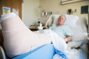 patient lying in hospital bed with broken leg bone wrapped in ca