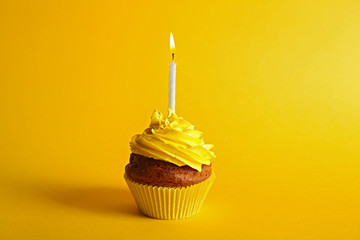 Fresh tasty cupcake with candle on yellow background