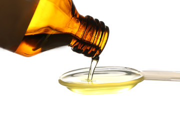 Pouring of fish oil from bottle into spoon, isolated on white