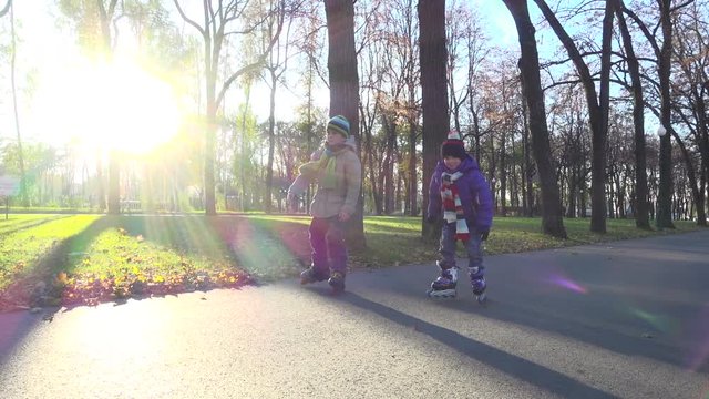 Two little boys ride in autumn park on rollerblades