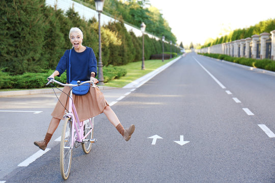 Funny young woman riding bicycle along road