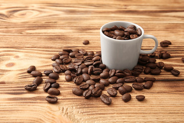 White cup with coffee beans on wooden background
